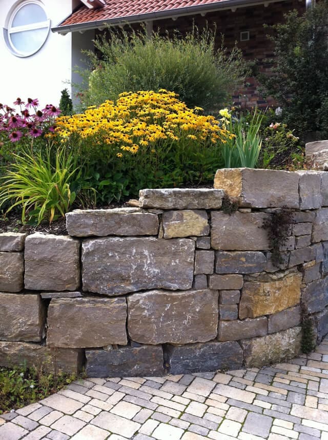 Garten Steinarbeiten Würzburg: Naturstein-Mauer zur Terrassierung mit Stauden